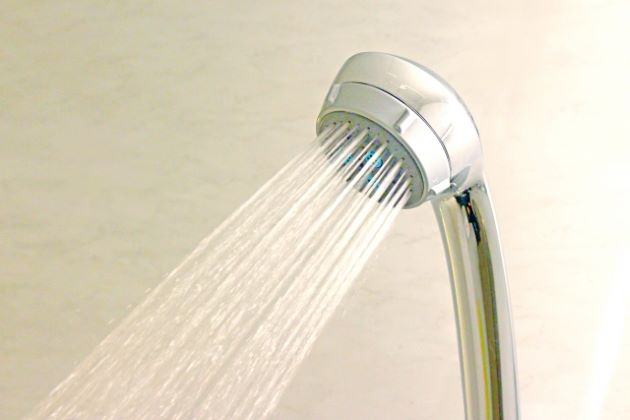 シャワーのヘッドから勢いよく出る水の写真