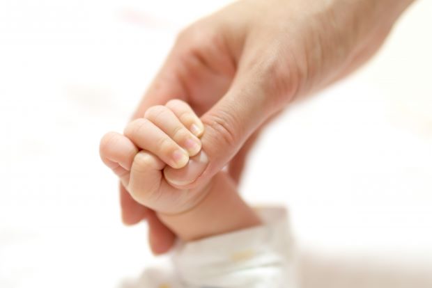 赤ちゃんの手を握るお母さんの手の写真